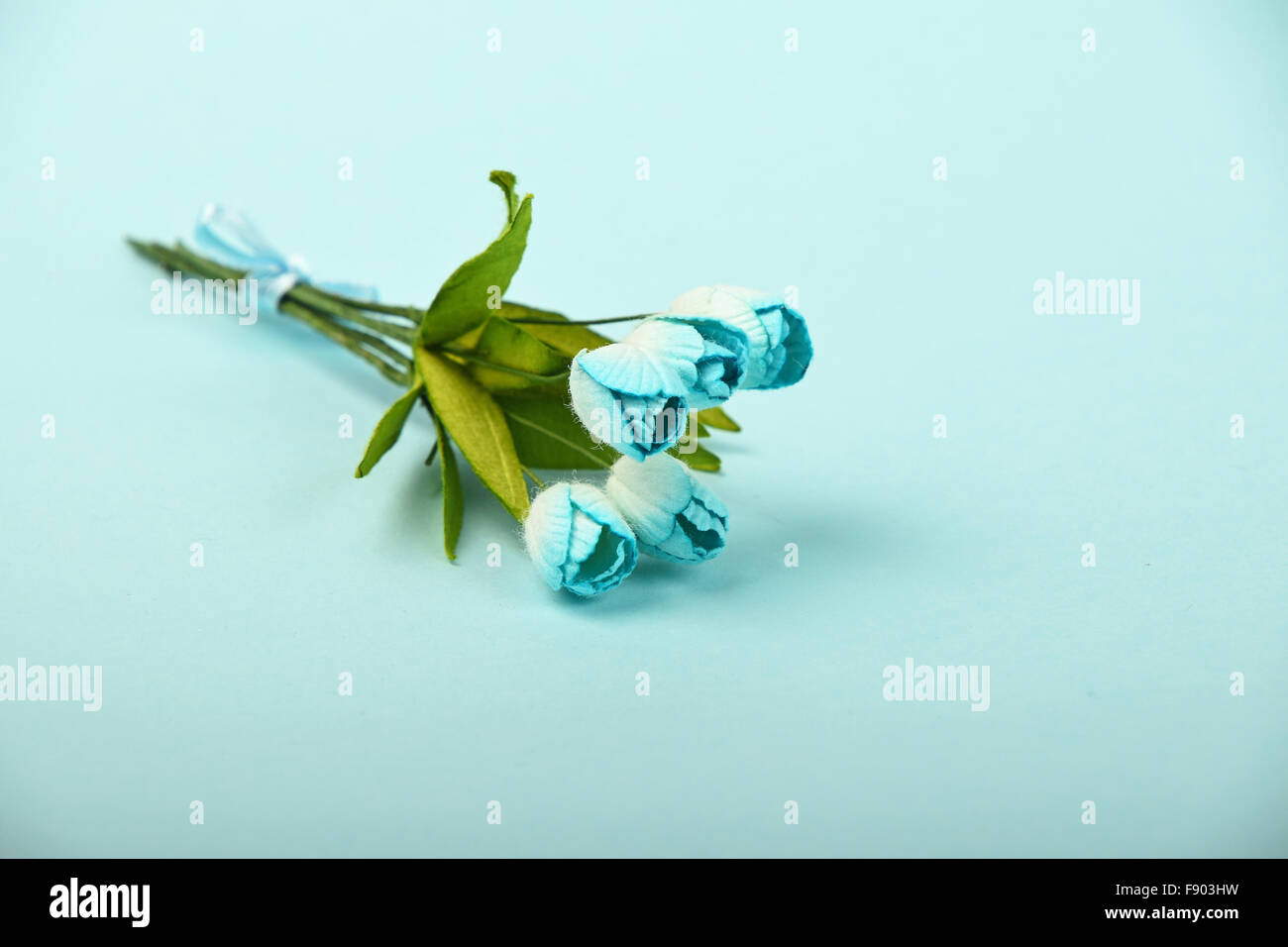 Un pequeño papel de morera tulipanes ramo de flores pequeñas sobre fondo azul de licitación Foto de stock