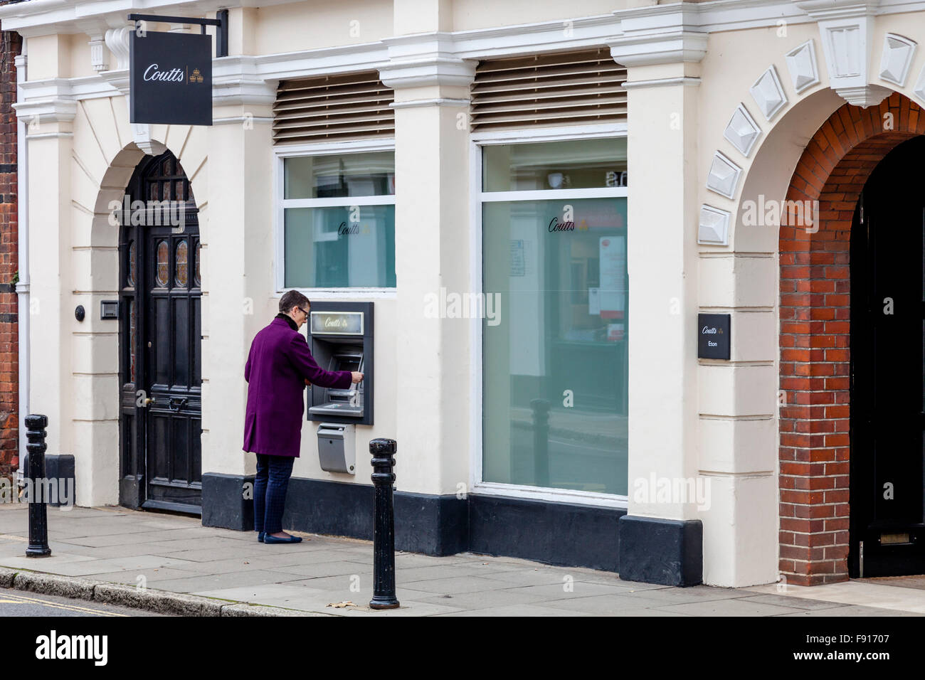 Una mujer con un cajero en Coutts Bank, High Street, Eton, Berkshire, Reino Unido Foto de stock