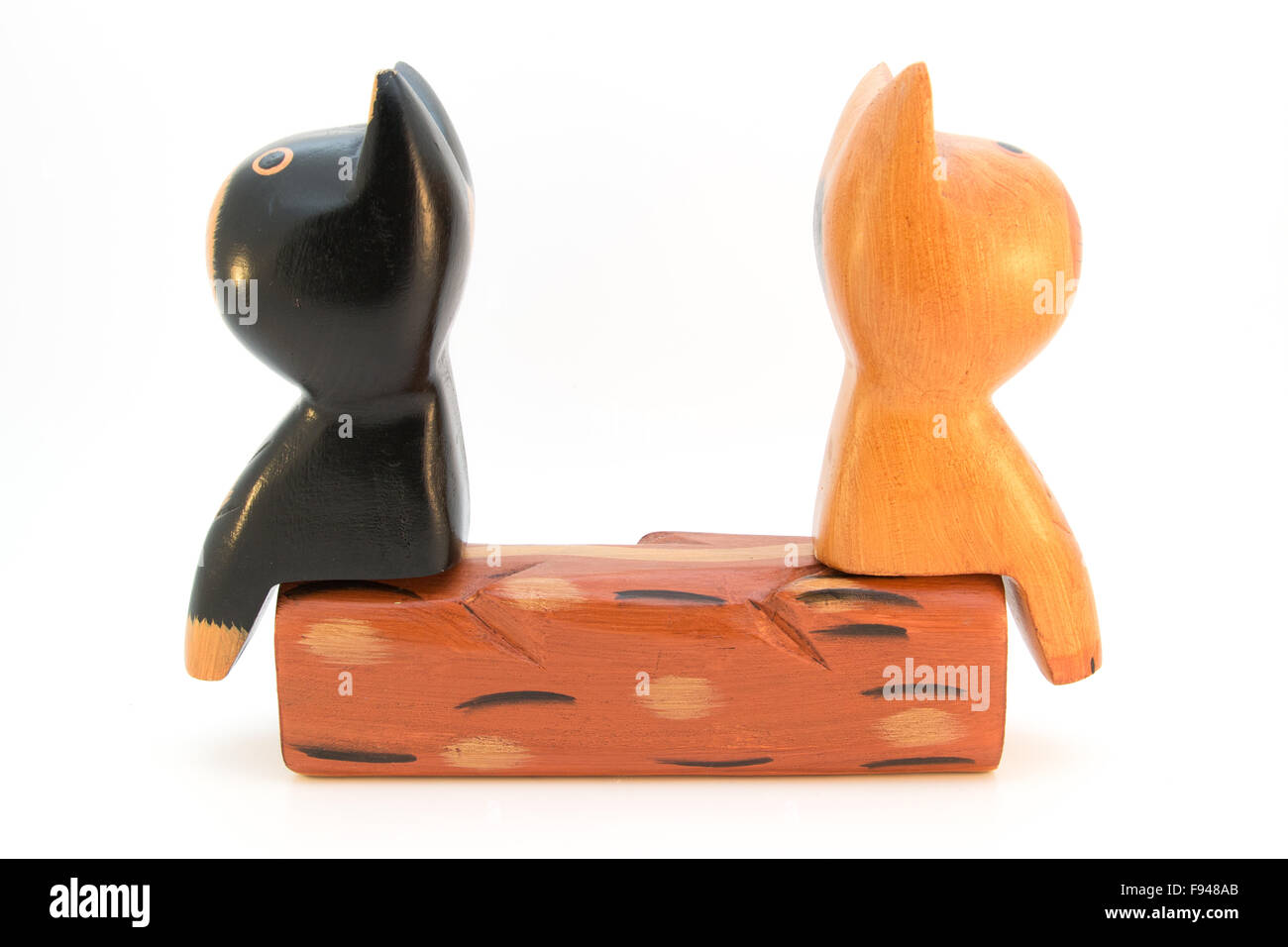 Dos gatos de madera sentados espalda con espalda en un banco Foto de stock