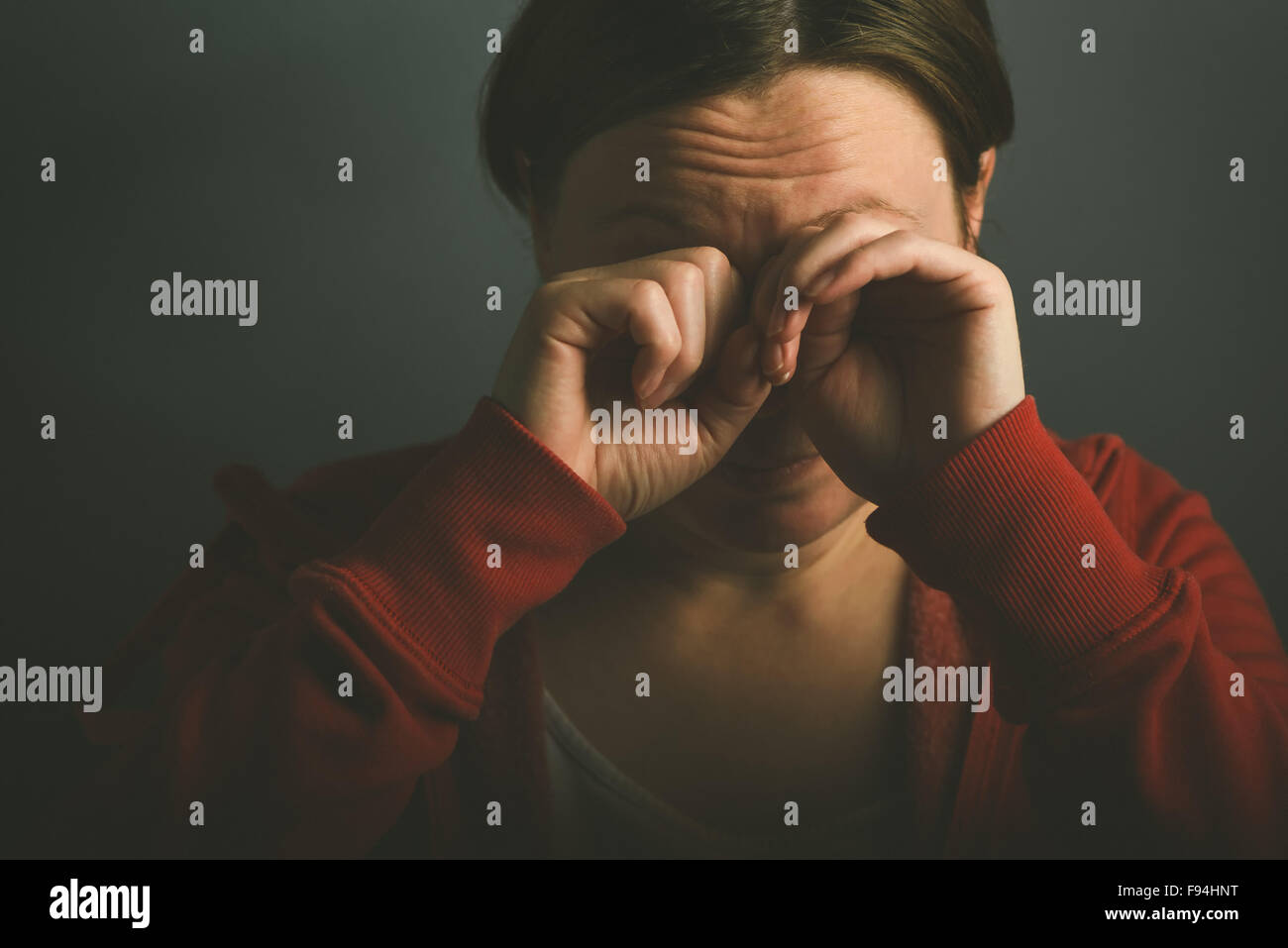 Mujer llorando en la desesperación, retrato de clave baja triste hembra adulto en habitación oscura Foto de stock