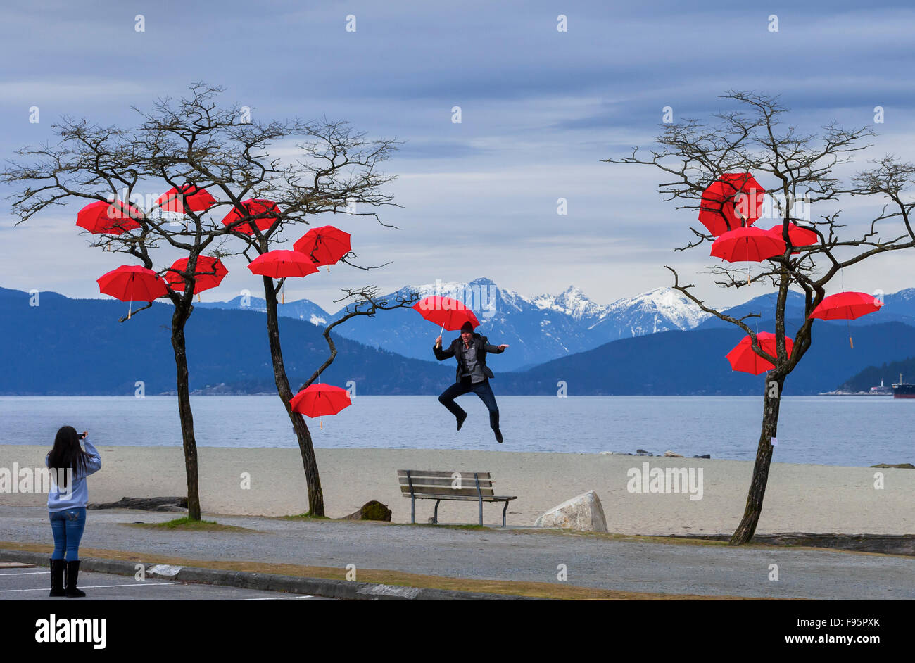Paraguas al aire libre muestra de arte con saltos hombre fotografiado bancos españoles, Vancouver, British Columbia, Canadá Foto de stock