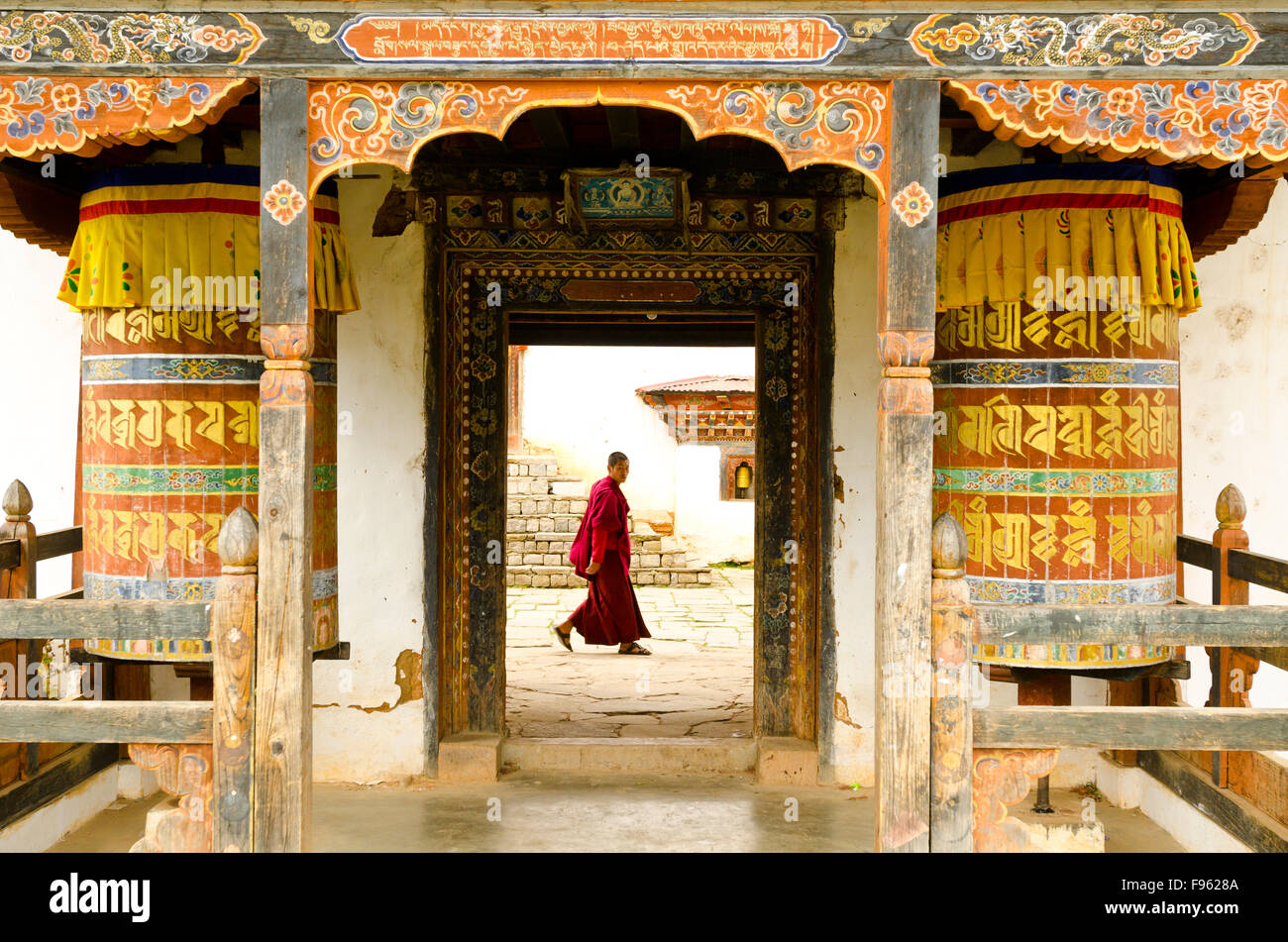 Un monje, pasando por las puertas delanteras de los bhutaneses monasterio Foto de stock