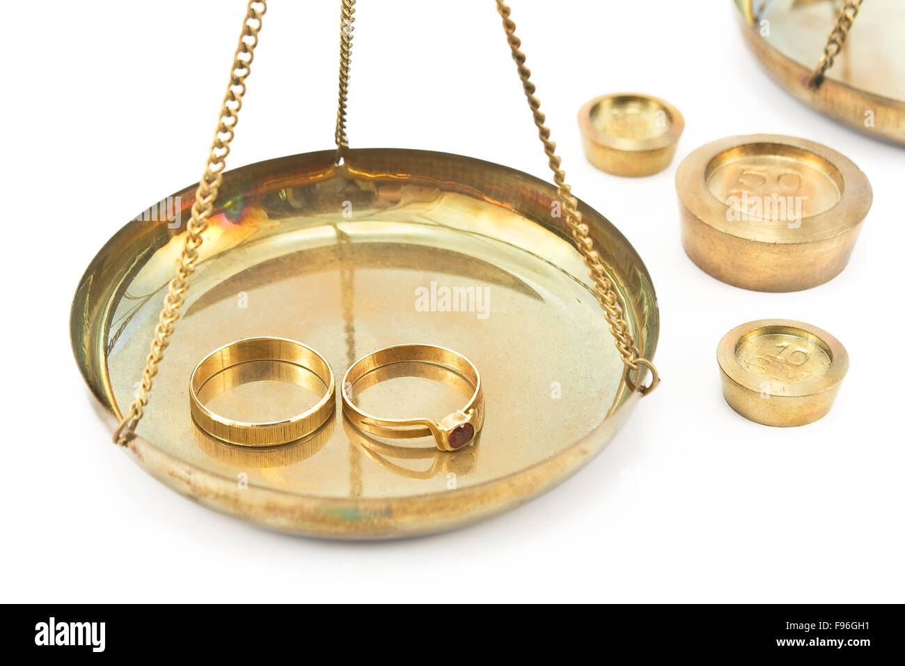 Balanza Báscula con anillos de boda de oro aislado en blanco Foto de stock