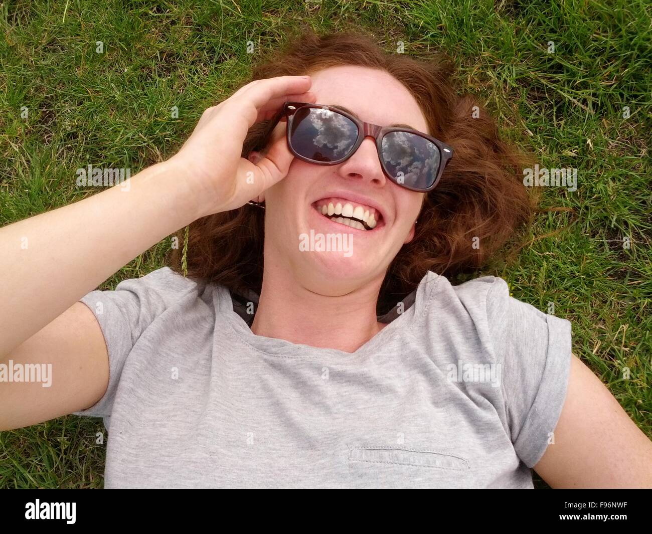 Mujer sonriente tumbado sobre el césped Foto de stock