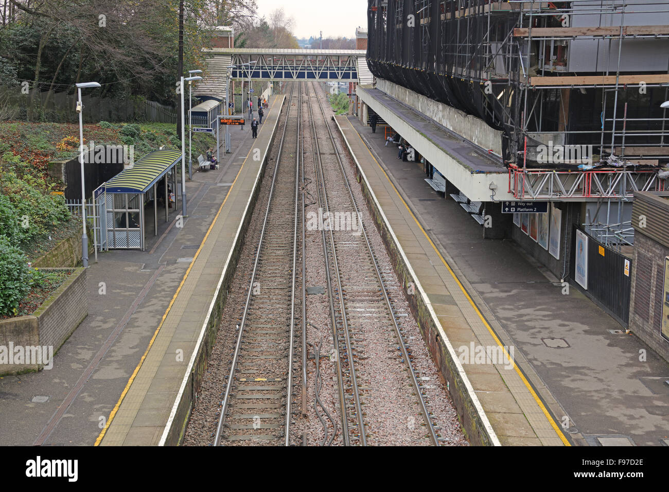 Él vista a lo largo de las plataformas hacia la señal de tercer carril las líneas electrificadas con pasajeros que esperan en la plataforma. Foto de stock