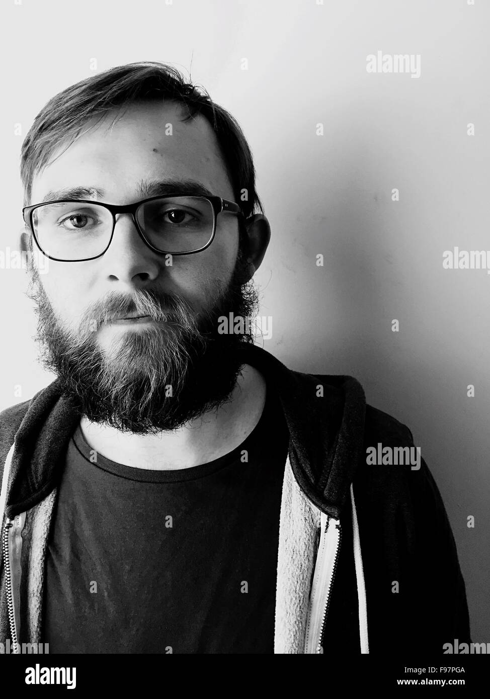 Retrato de hombre con anteojos de pie contra la pared en casa Foto de stock