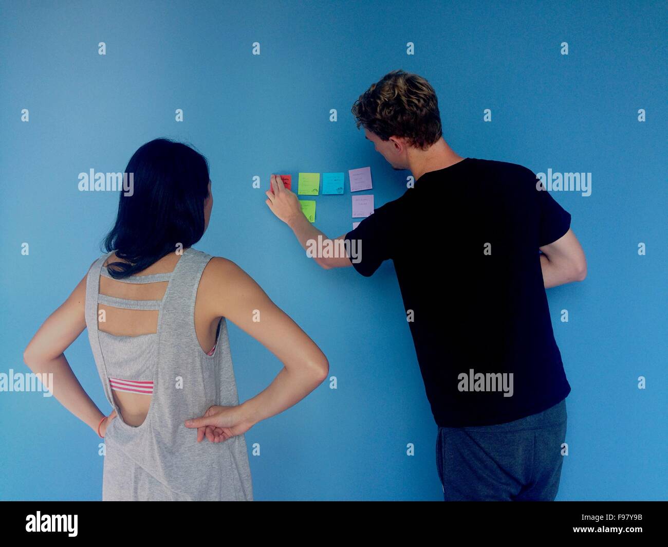 Hombre Notas adhesivas pegadas en la pared azul por mujer Fotografía de