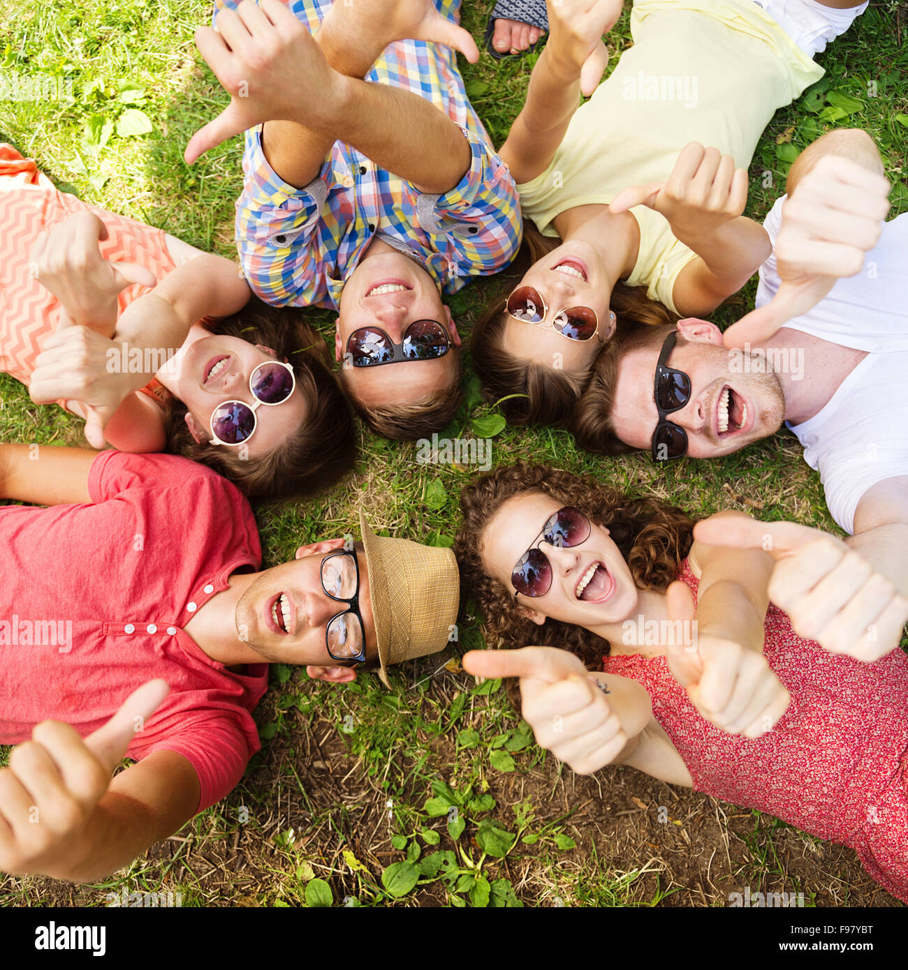 Grupo de jóvenes divirtiéndose en el parque, recostados sobre el pasto Foto de stock