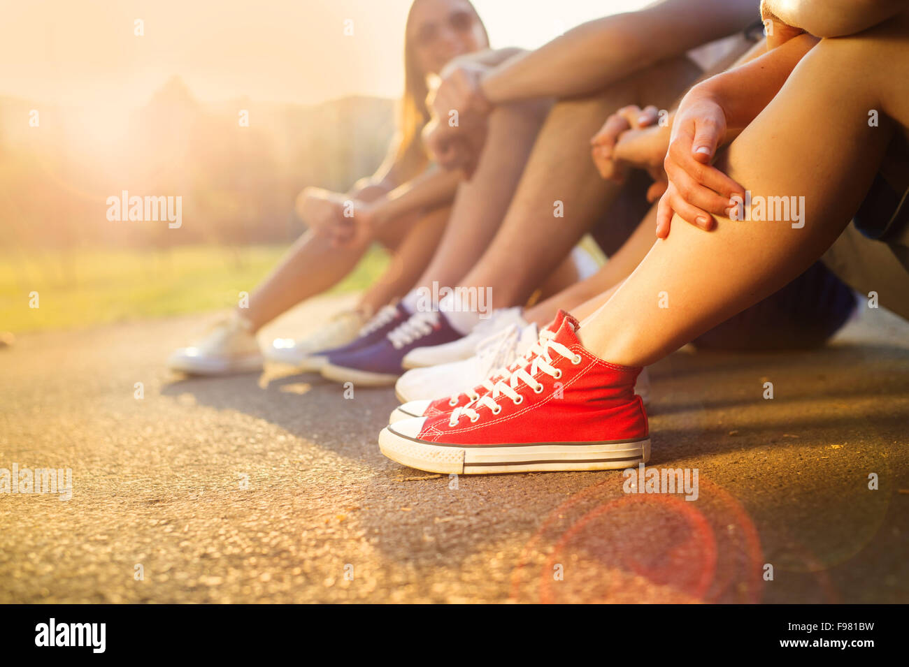 Piernas y zapatillas de adolescentes, chicos y chicas, sentados en la acera  Fotografía de stock - Alamy