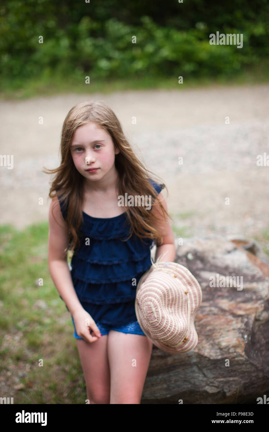Una chica joven con el pelo largo se inclina contra una roca. Foto de stock