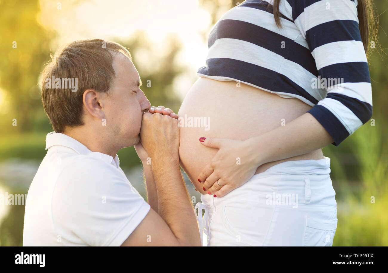 El hombre es besar el vientre de la mujer embarazada en la naturaleza Foto de stock