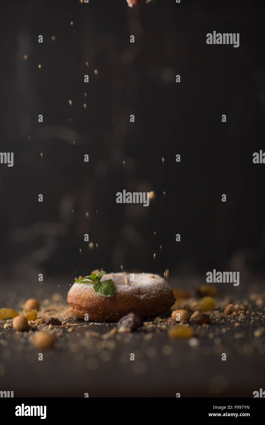 Donut de azúcar espolvoreado con migajas sobre fondo de piedra oscura Foto de stock