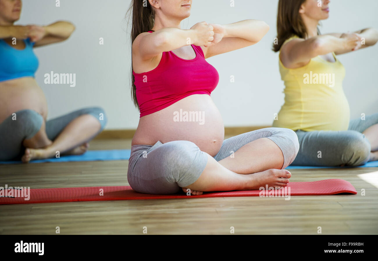 Grupo de mujeres jóvenes embarazadas haciendo ejercicio de relajación en el ejercicio de mat Foto de stock