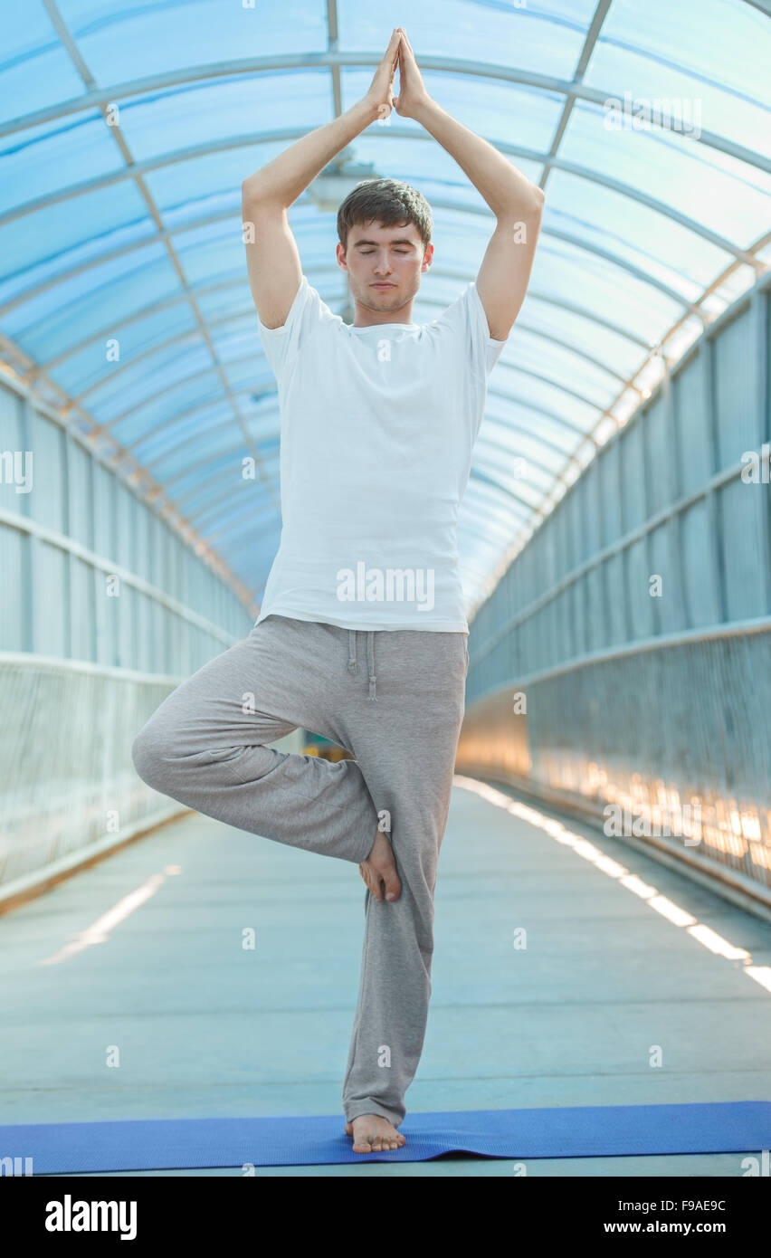 Colocar joven prácticas yoga en el puente Foto de stock