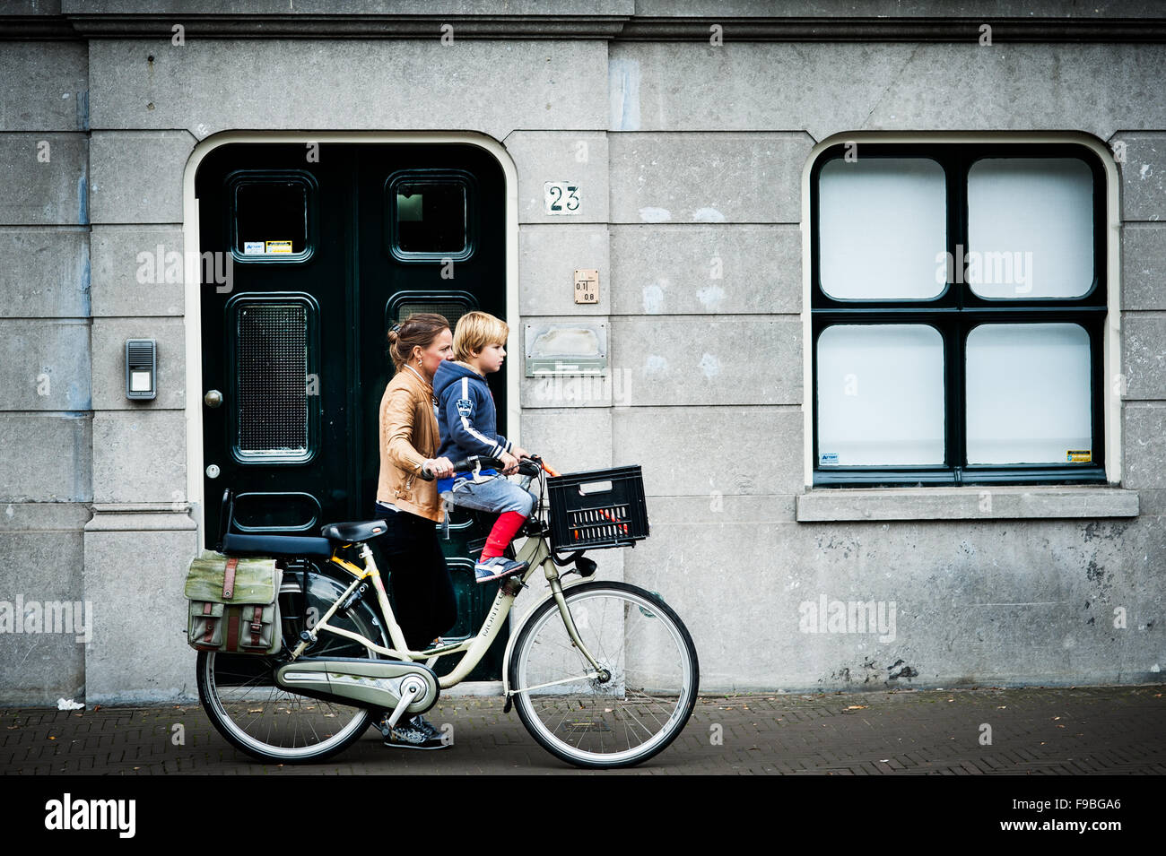 Una mujer caries a su hijo en su bicicleta, muy habitual ver en las calles holandesas. Foto de stock