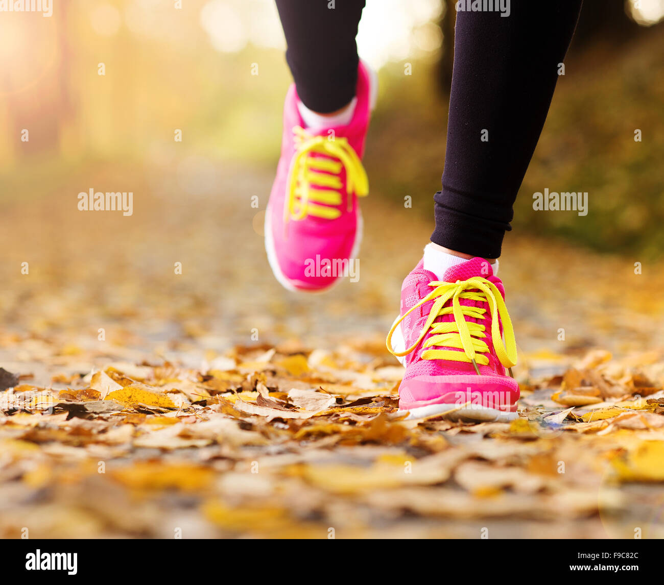 Cerca de los pies de un corredor corriendo en hojas de otoño ejercicio de entrenamiento Foto de stock