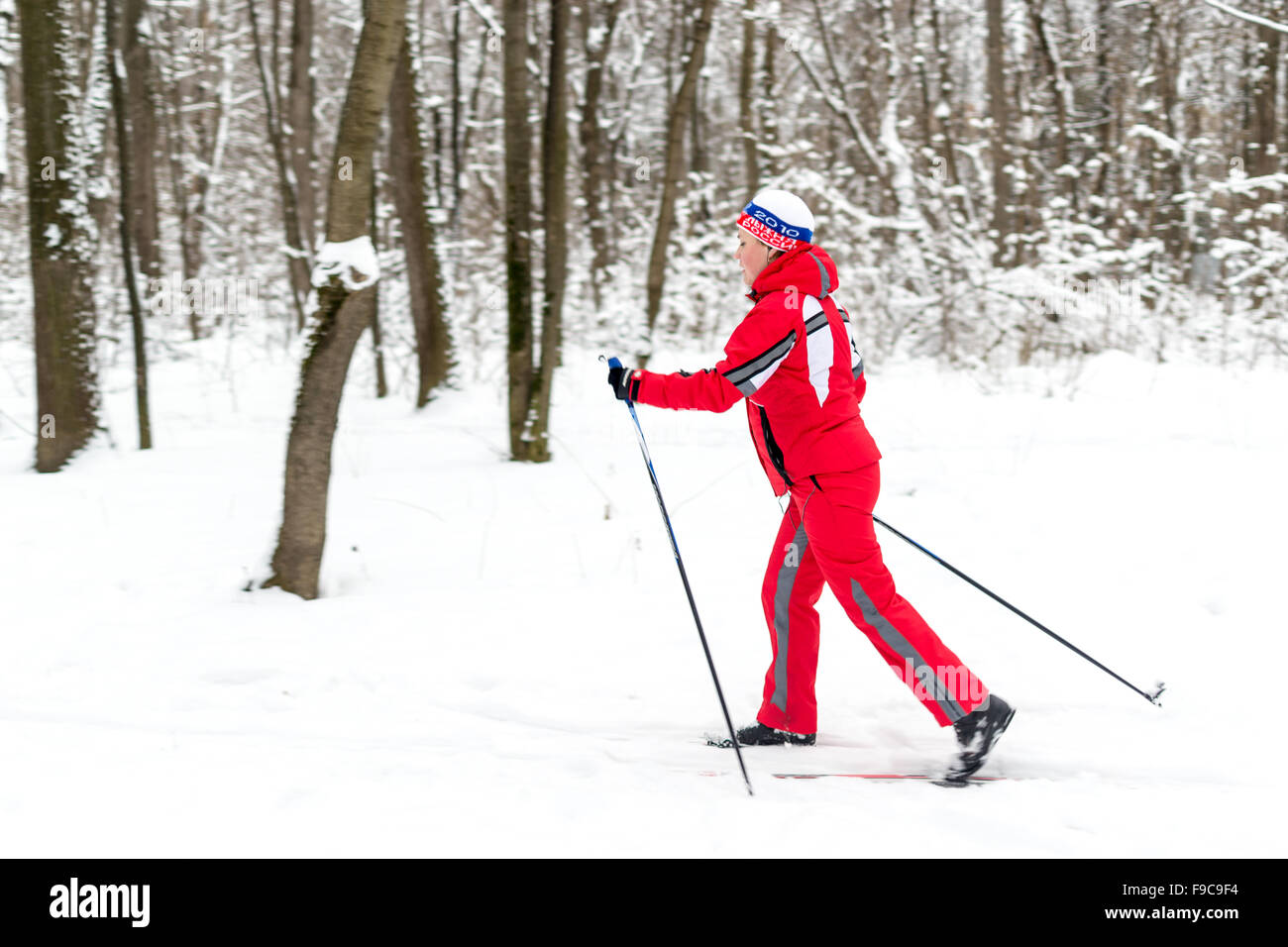 Mujer esquiador en rojo brillante ropa de esquí esquí ejerce por un parque público local en Ufa, Rusia Foto de stock