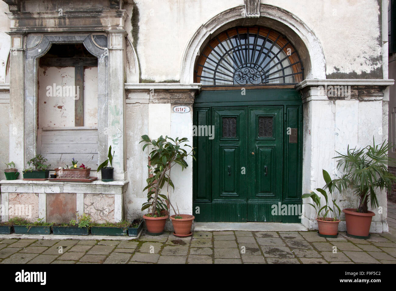 Un edificio con una puerta verde y plantas Foto de stock