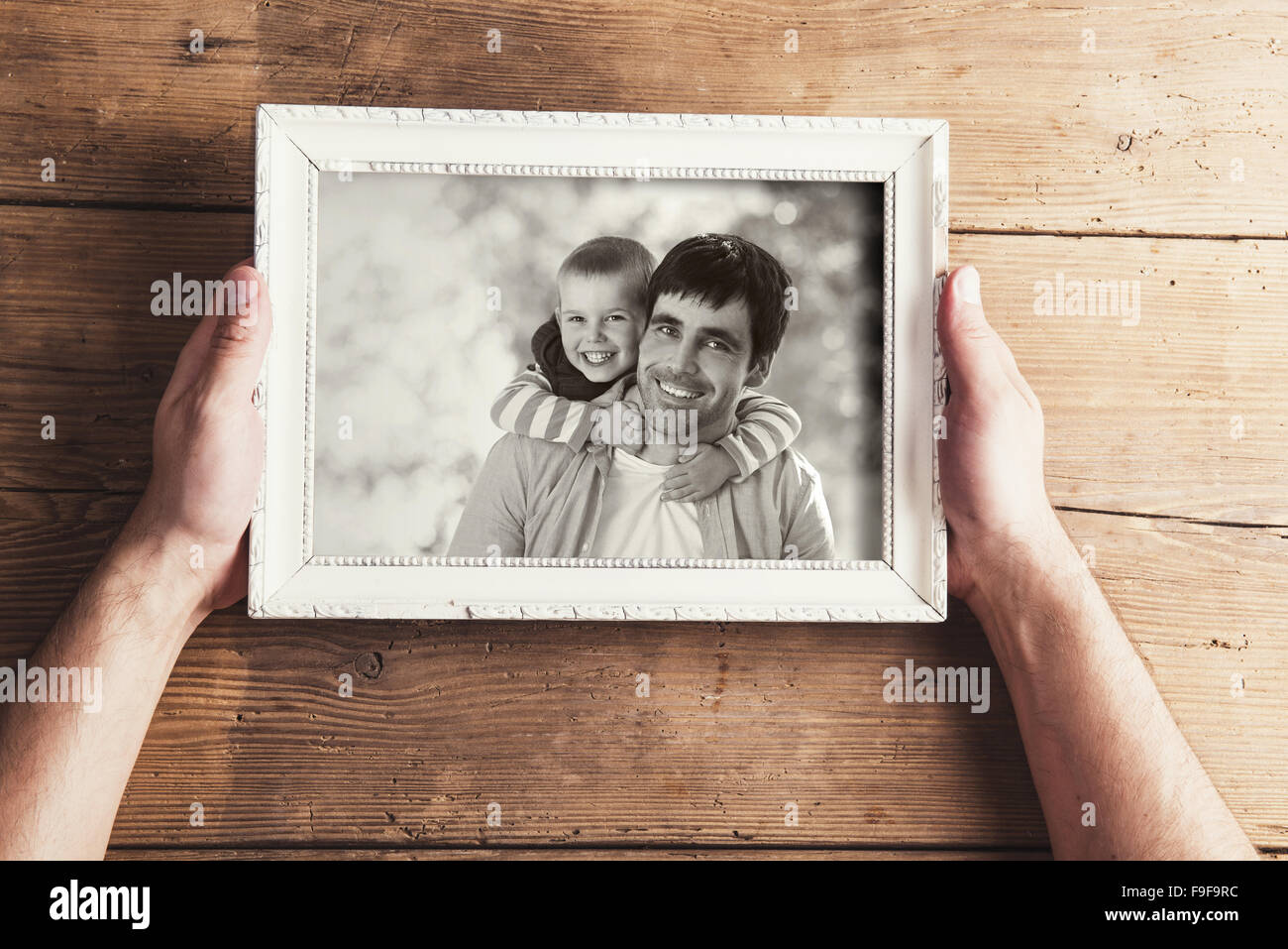 Hombre sujetando un cuadro con la foto de familia sobre un fondo de