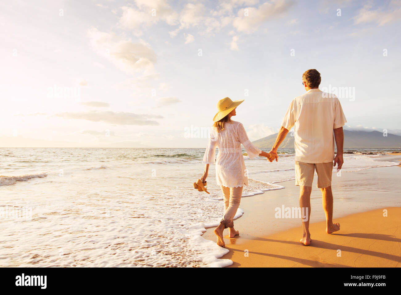 Alegre romántica pareja de mediana edad disfrutando hermoso atardecer pasear por la playa. Concepto de estilo de vida de jubilación Vacaciones viajes Foto de stock
