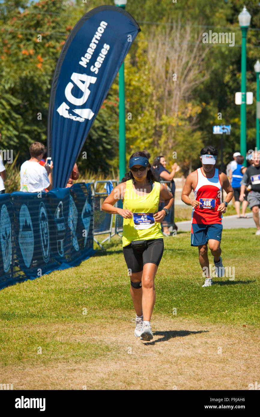Una hembra hispanic runner casi cruzando la línea de meta en el Maratón de Norcal Foto de stock