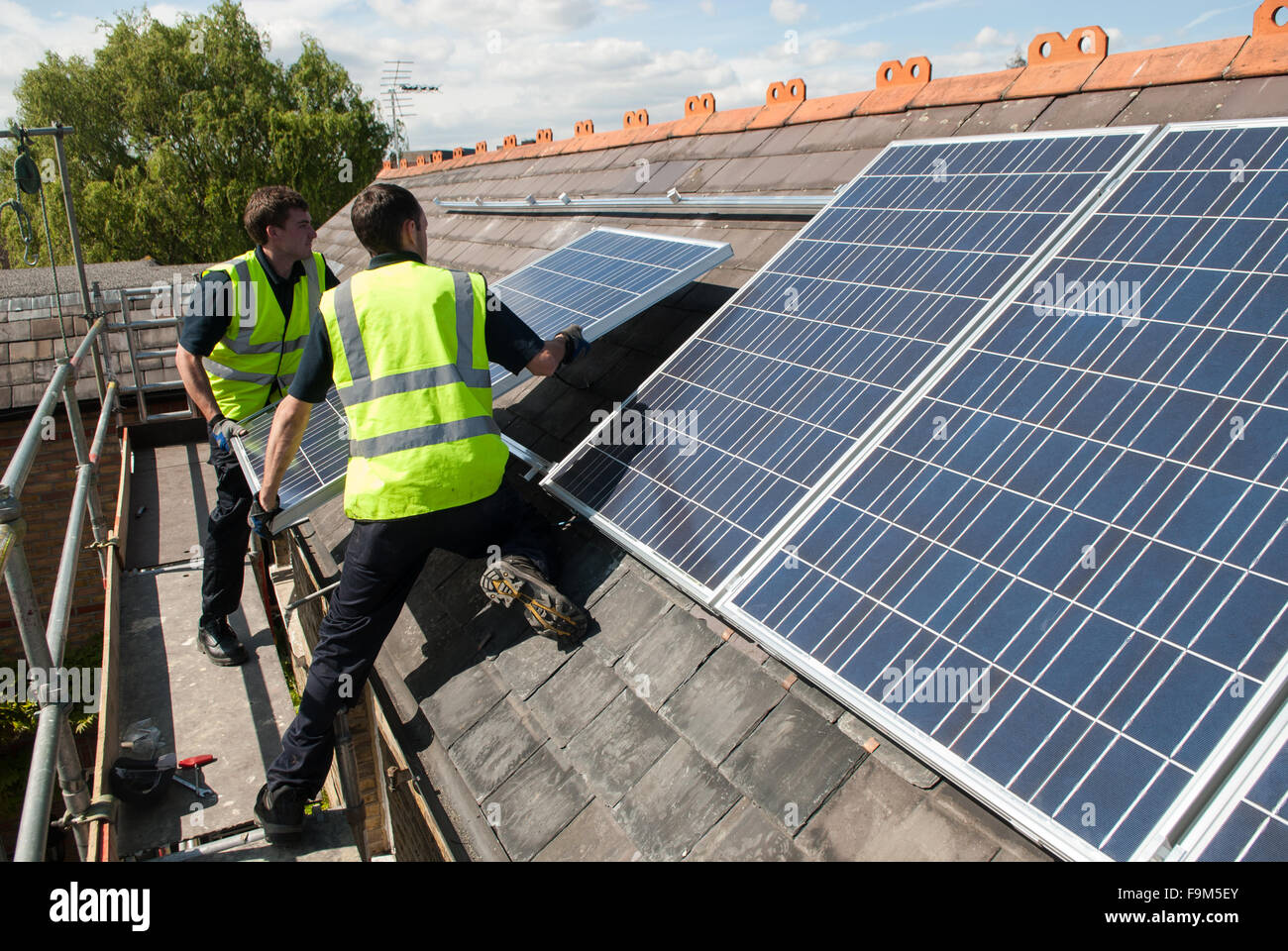 Los trabajadores instalar paneles solares fotovoltaicos en el tejado de pizarra de una casa victoriana en Londres, Inglaterra. Foto de stock