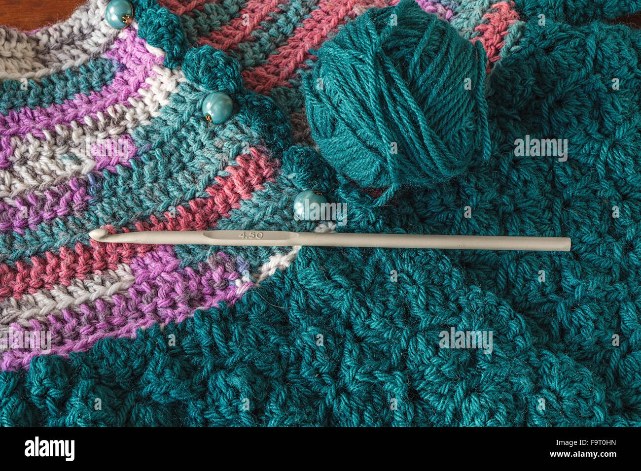 Crochet suéter de bebé con un ganchillo y bola de hilo. Foto de stock