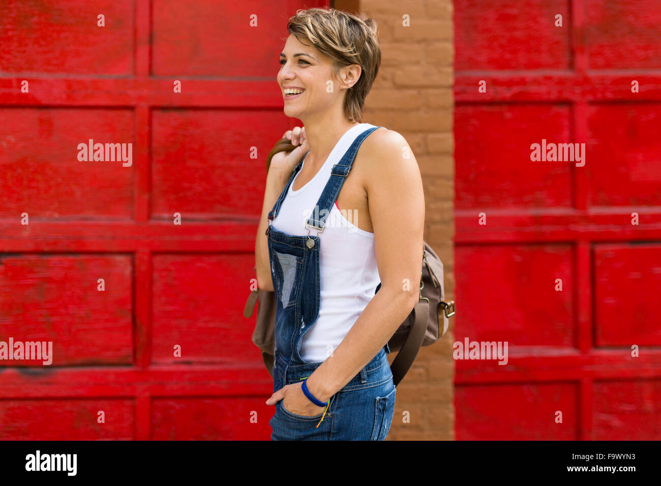 Rubia sonriente mujer vistiendo pantalones con peto delante de un fondo rojo  Fotografía de stock - Alamy