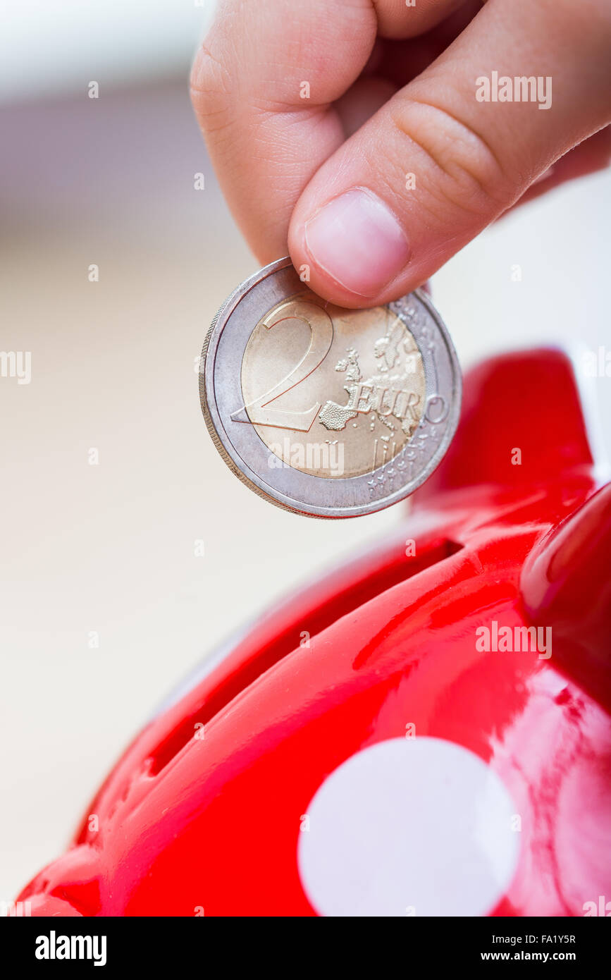 Niño arrojados a Piggy la moneda de dos euros. Foto de stock