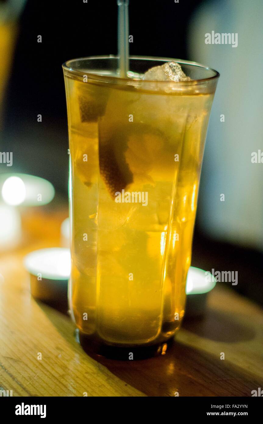Beba alcohol con limón y hielo en una mesa de madera con velas. Foto de stock