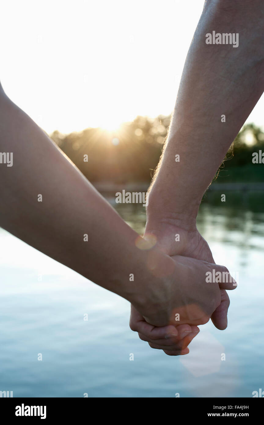 Cerca de la pareja en el amor cogidos de la mano durante la puesta de sol, Baviera, Alemania Foto de stock