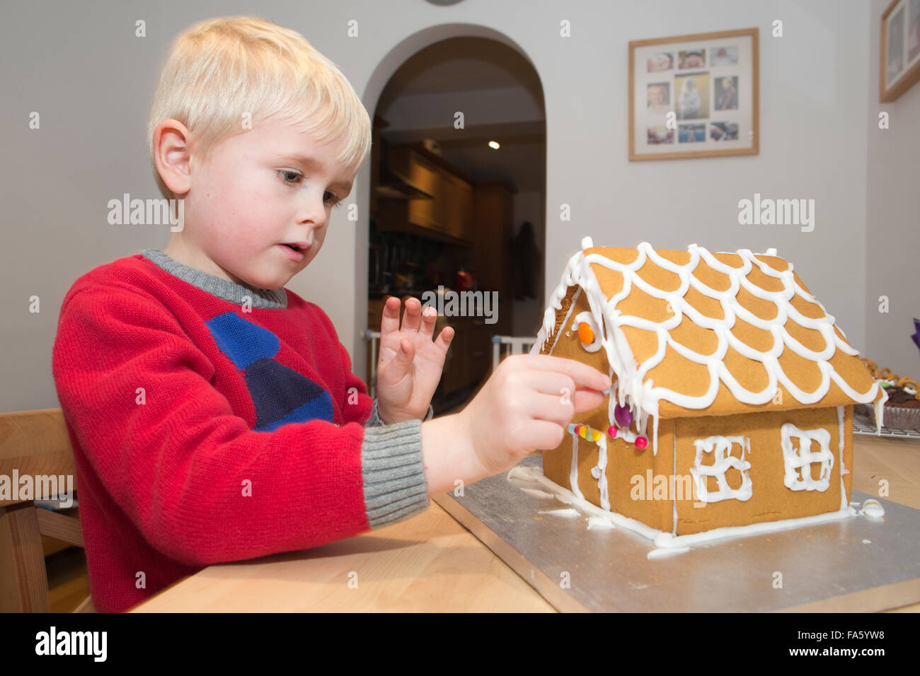 Niño de 5 años construir una casa hecha de pan de jengibre gingerbread antes de las festividades navideñas, REINO UNIDO Foto de stock
