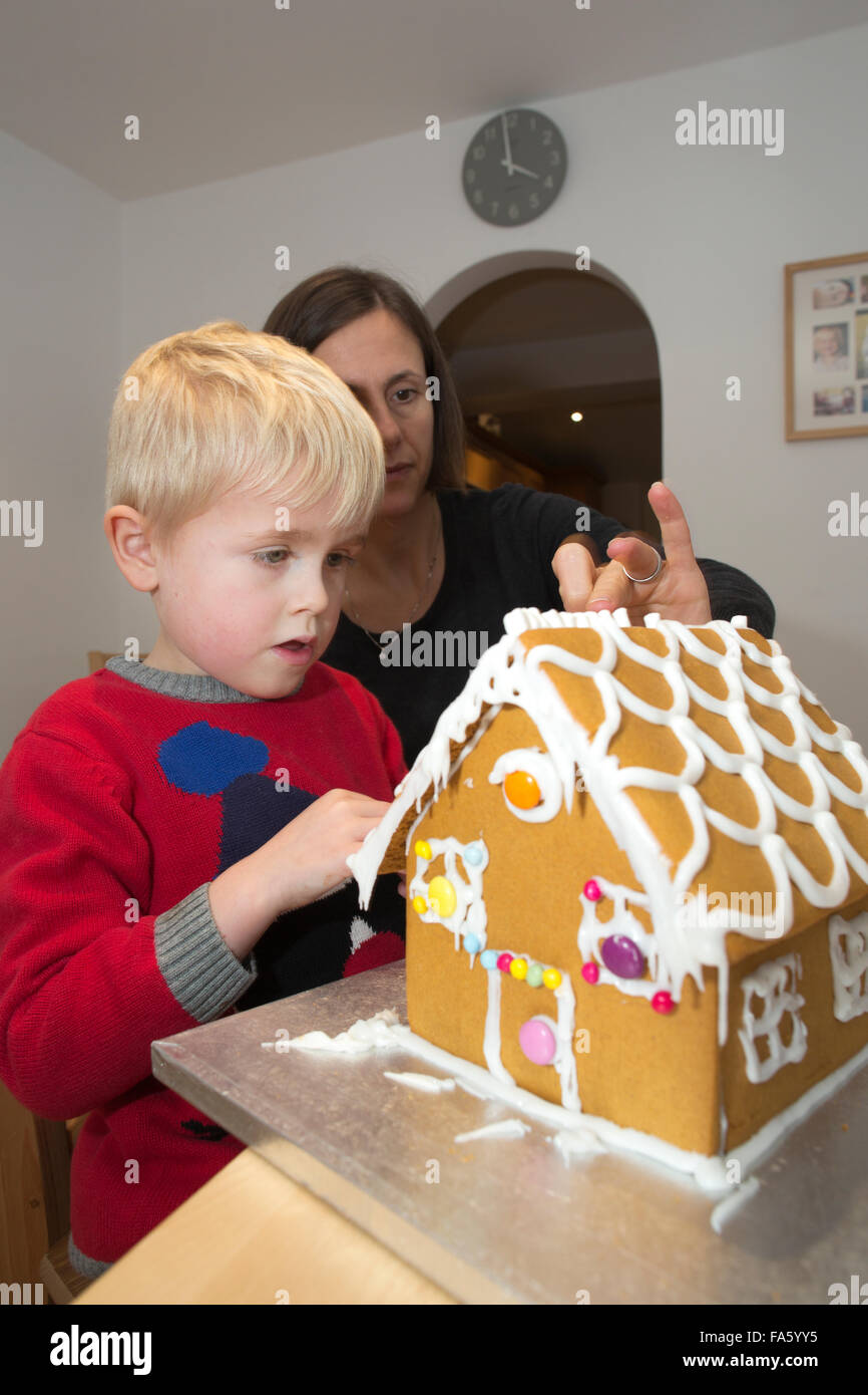 Niño de 5 años construir una casa hecha de pan de jengibre gingerbread antes de las festividades navideñas, REINO UNIDO Foto de stock