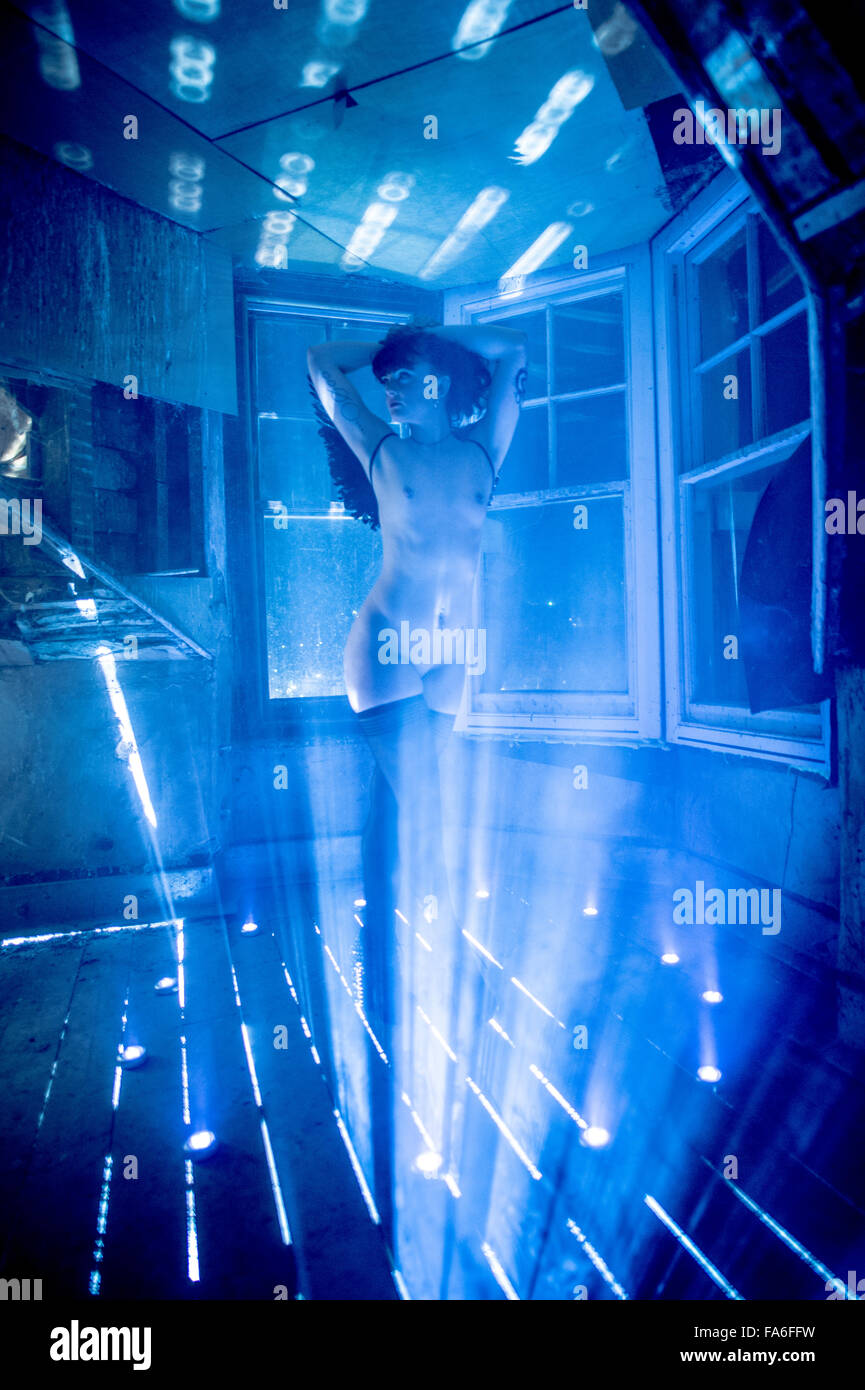 Una joven mujer cuerpo desnudo nude desnuda chica sola en un edificio abandonado abandonado por la noche luciendo medias negras y un par de alas de angel oscuro, promulgando una de sus imagen