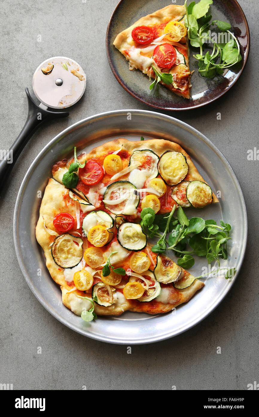 Pizza vegetariana con calabacín,cebolla,tomates cherry,berros y mozarella Foto de stock