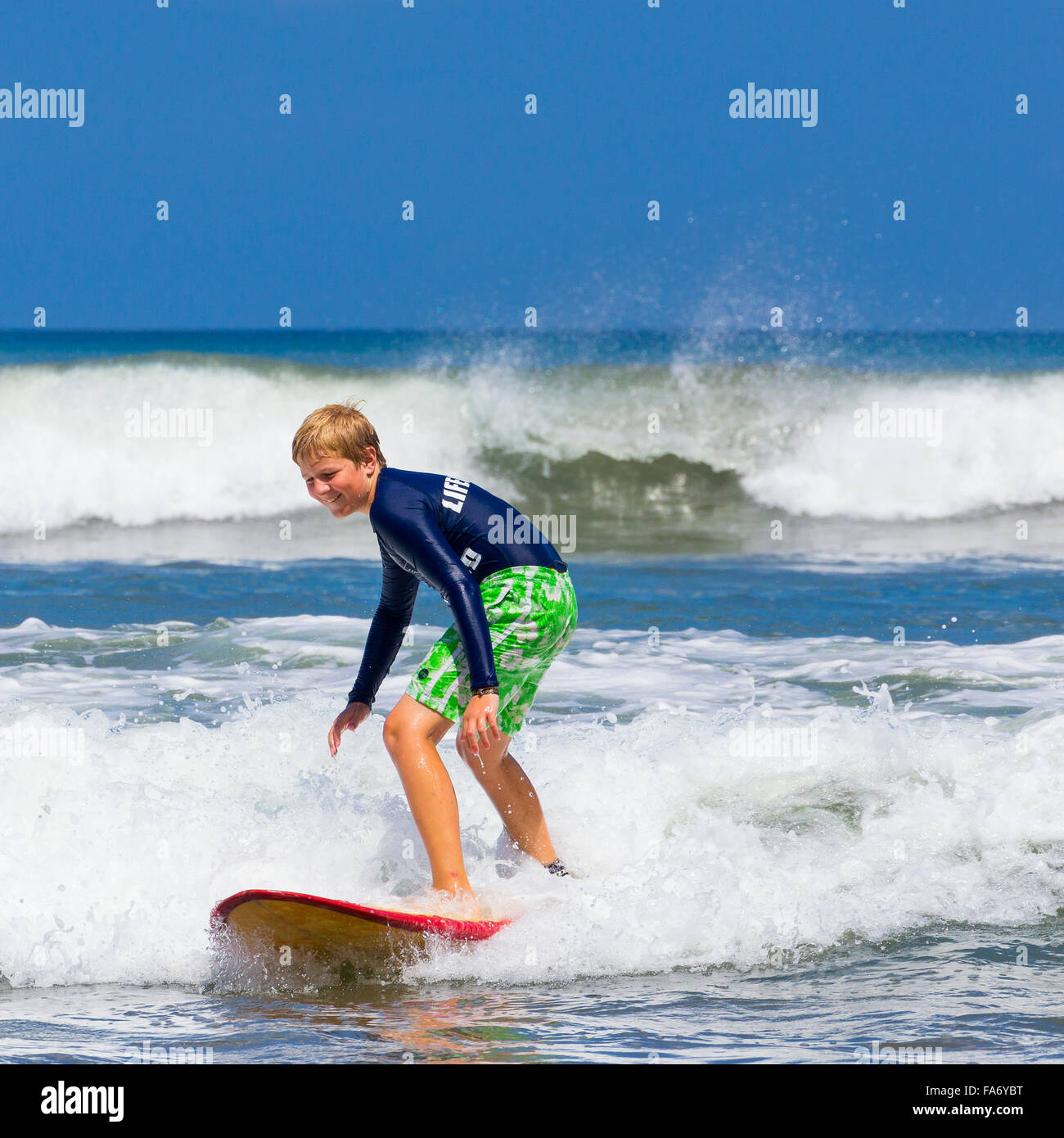 Un muchacho, de 12 años, surf, Kuta, Legian, playa y surf paradise, Bali, Indonesia Foto de stock