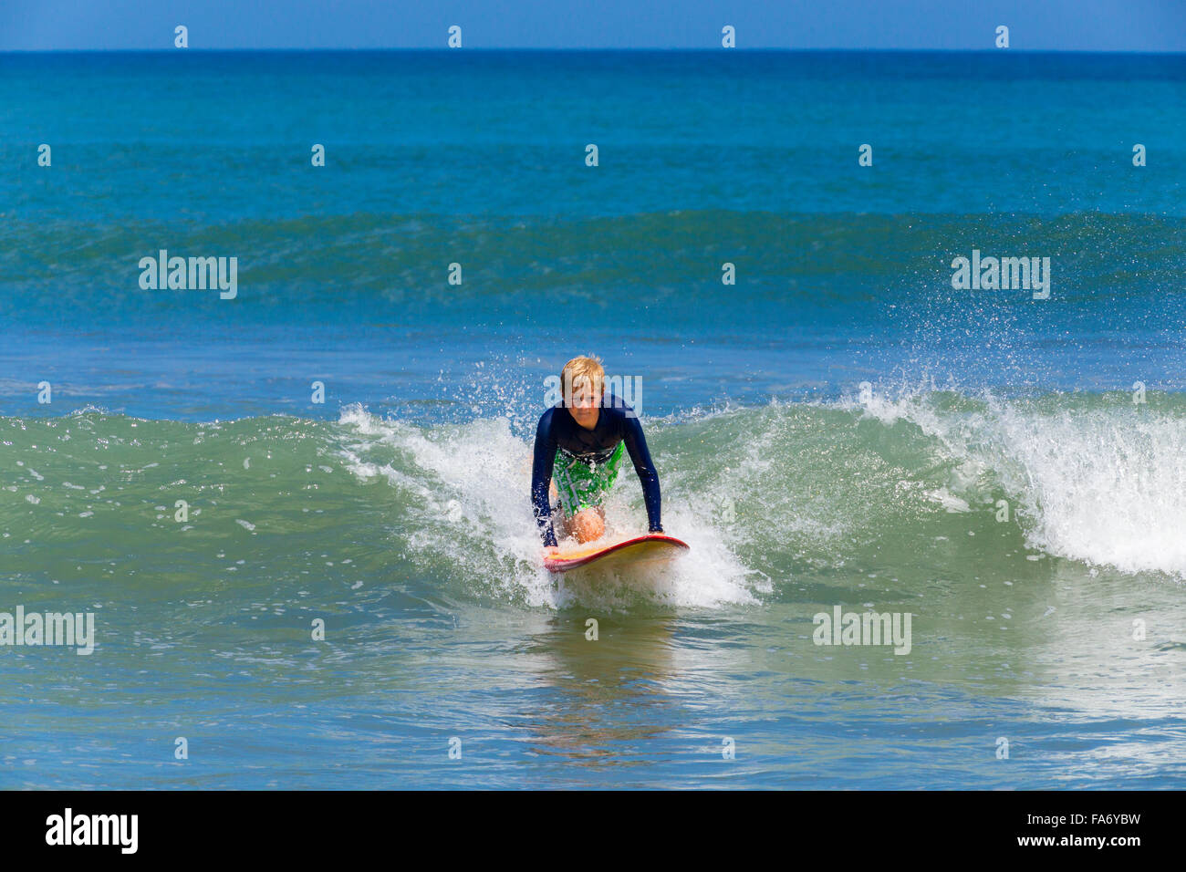 Un muchacho, de 12 años, surf, Kuta, Legian, playa y surf paradise, Bali, Indonesia Foto de stock