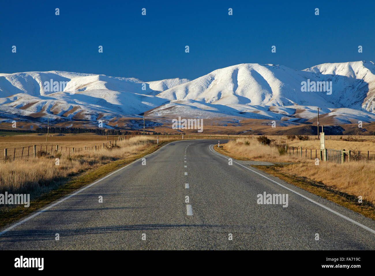 Carretera cerca de Hawkdun Oturehua y rango, Maniototo, Central Otago, Isla del Sur, Nueva Zelanda Foto de stock