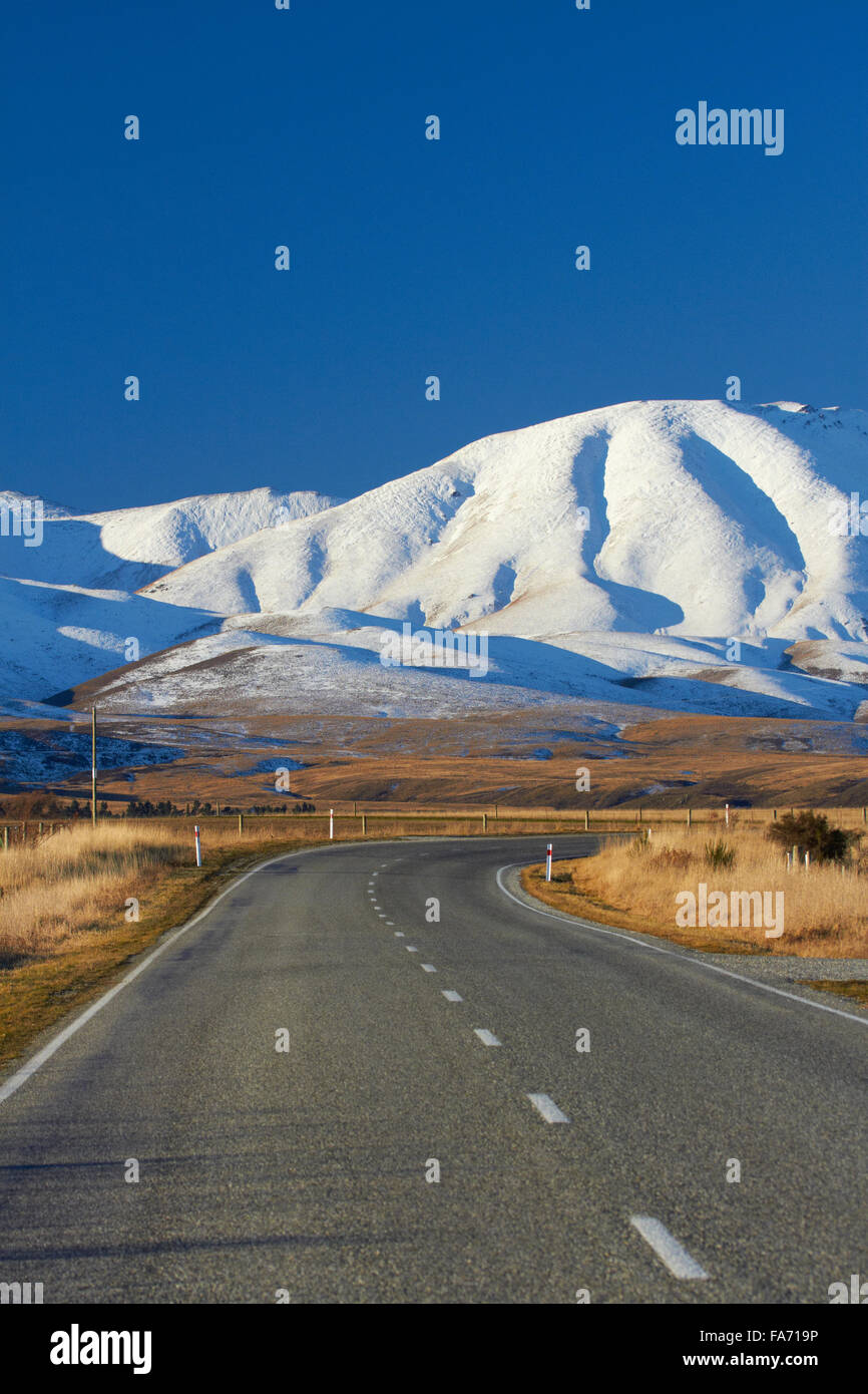 Carretera cerca de Hawkdun Oturehua y rango, Maniototo, Central Otago, Isla del Sur, Nueva Zelanda Foto de stock