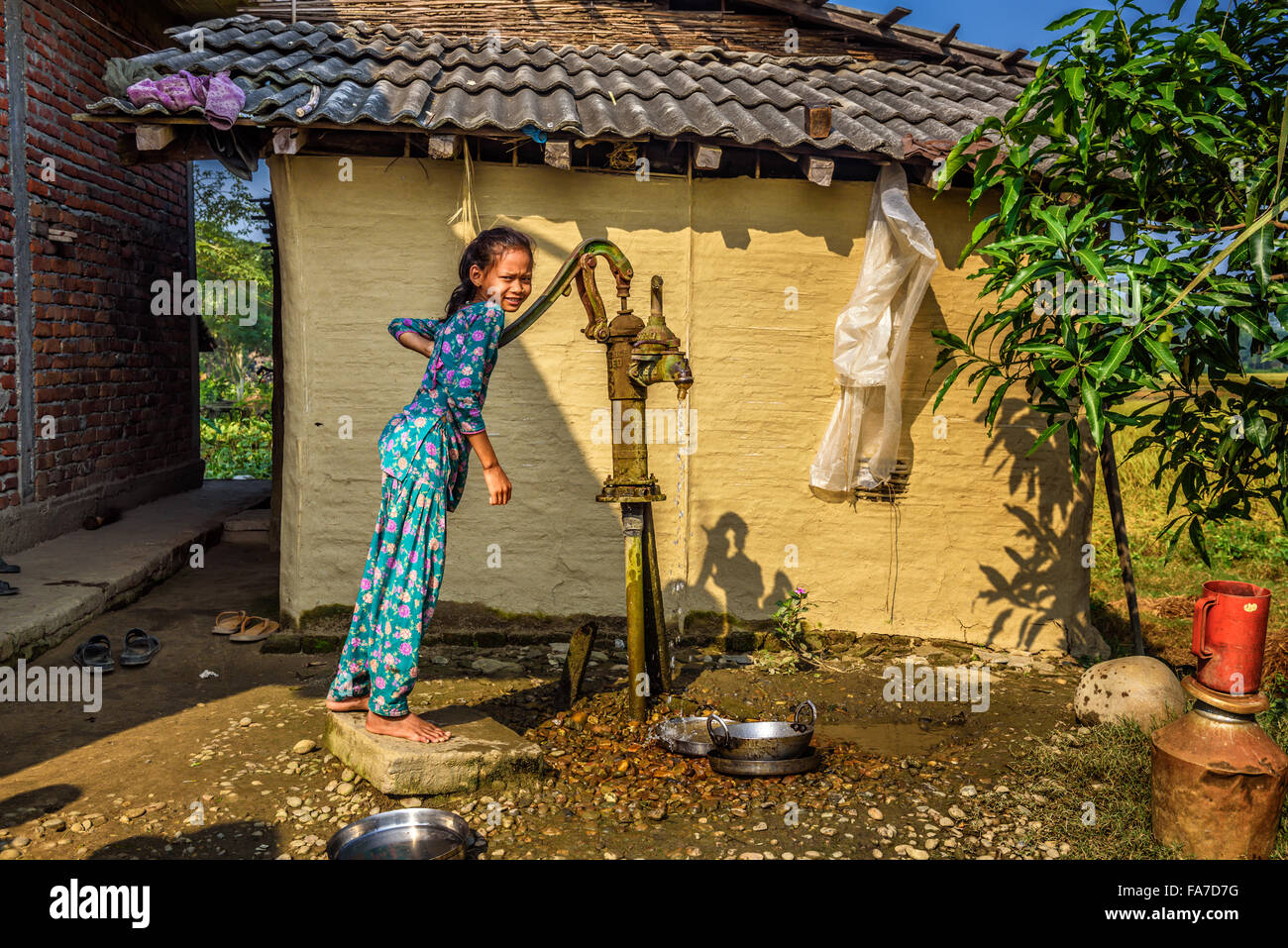Chica joven nepalés obtiene agua de un pozo en la aldea Foto de stock