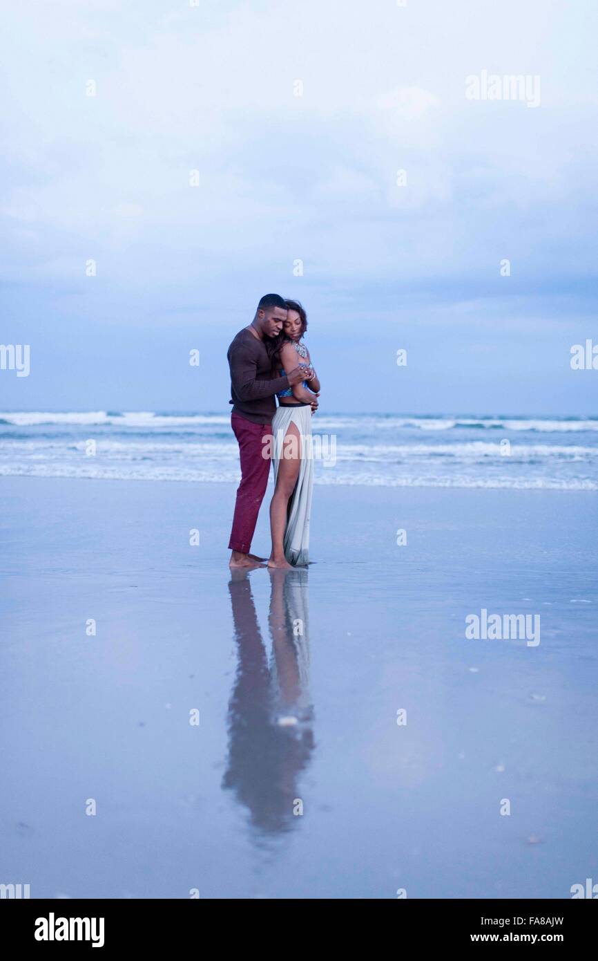 Par de pie en la playa, abrazando Foto de stock