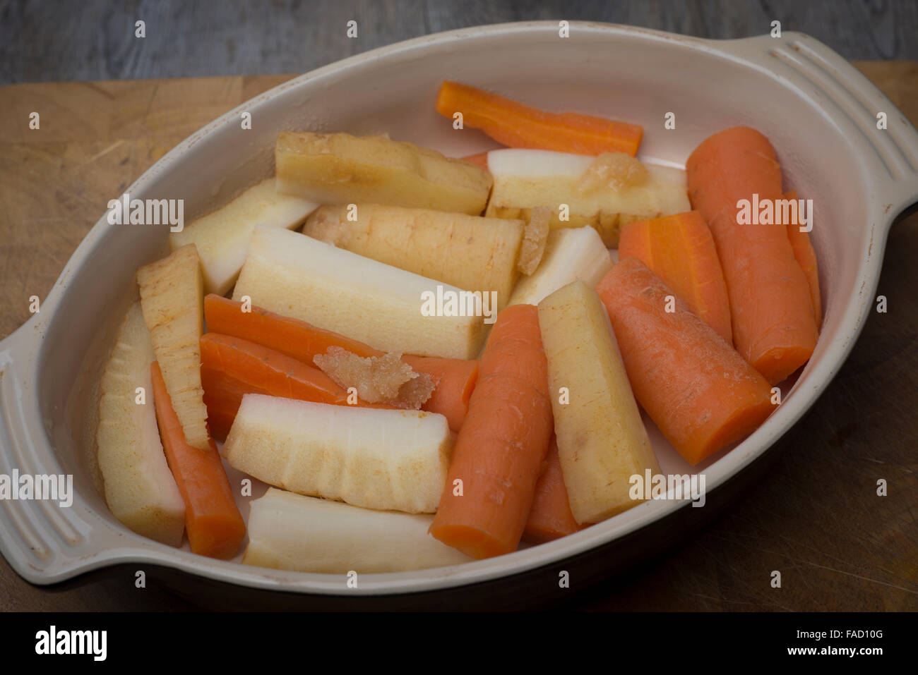 Las zanahorias y la chirivía preparado en un plato listo para asar con miel, aceite y hierbas Foto de stock