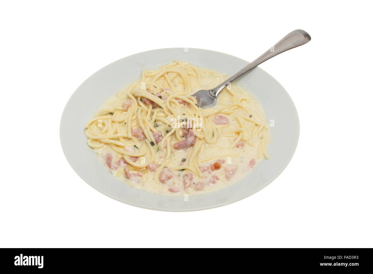 Espaguetis Carbonara en un recipiente con un tenedor contra un blanco aislado Foto de stock