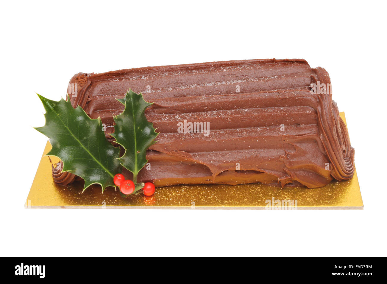 Yule log de chocolate decorada con una ramita de acebo aislado contra un blanco Foto de stock