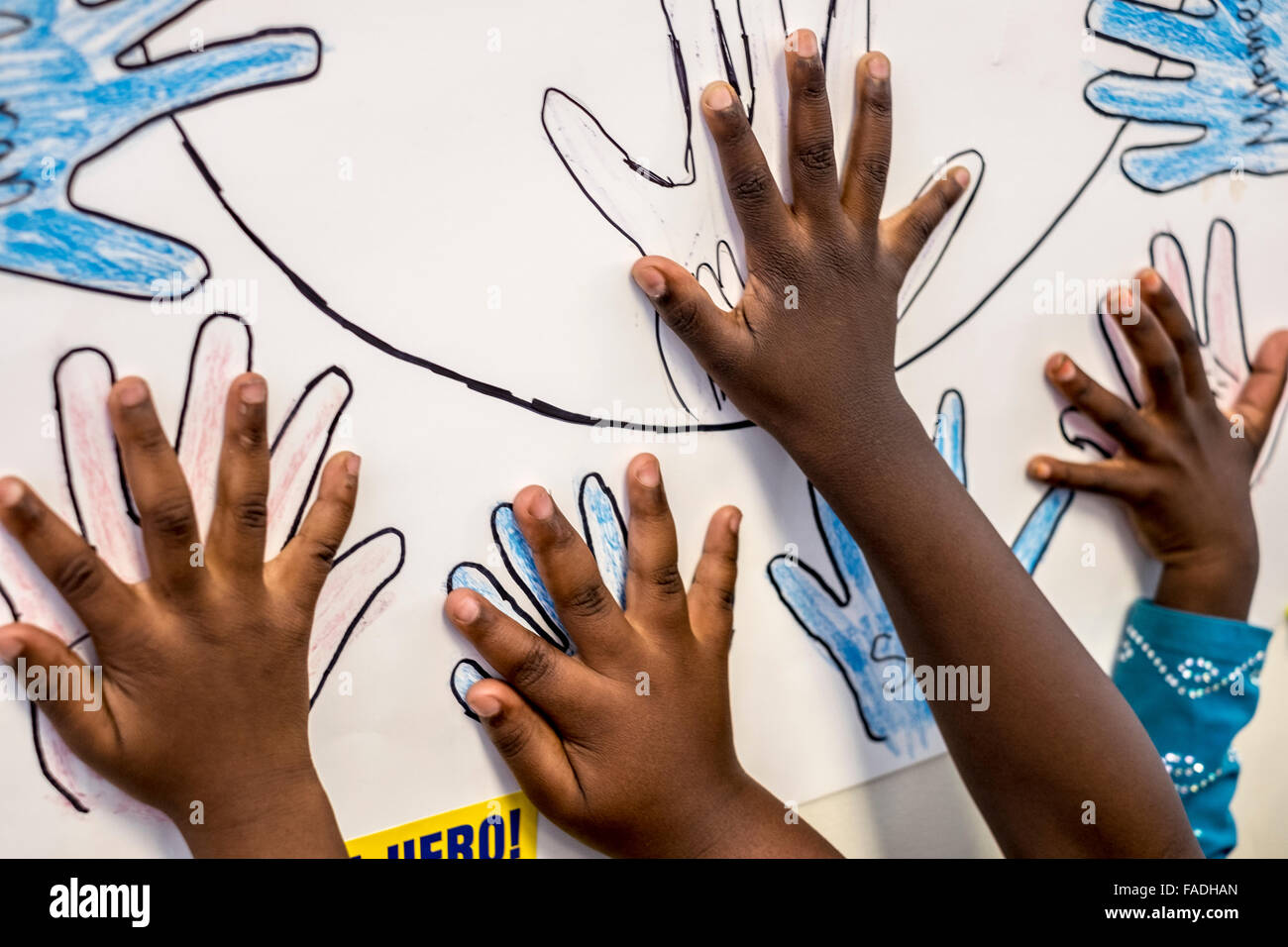 Cuatro manos de niños refugiados somalíes llegan en un juego que están jugando durante la escuela de verano. Foto de stock