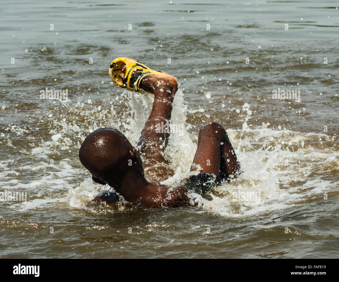 Niño jugando en el agua sucia en Freetown, Sierra Leone. Foto de stock