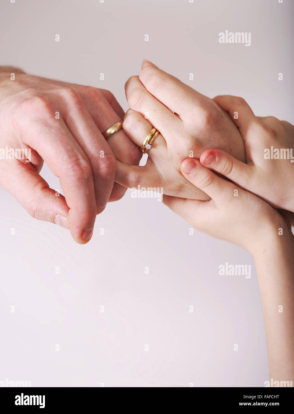 Matrimonio joven mantenga las manos con los anillos de bodas presente en las manos de los niños, el agarre a la madre sosteniendo la relación juntos Foto de stock