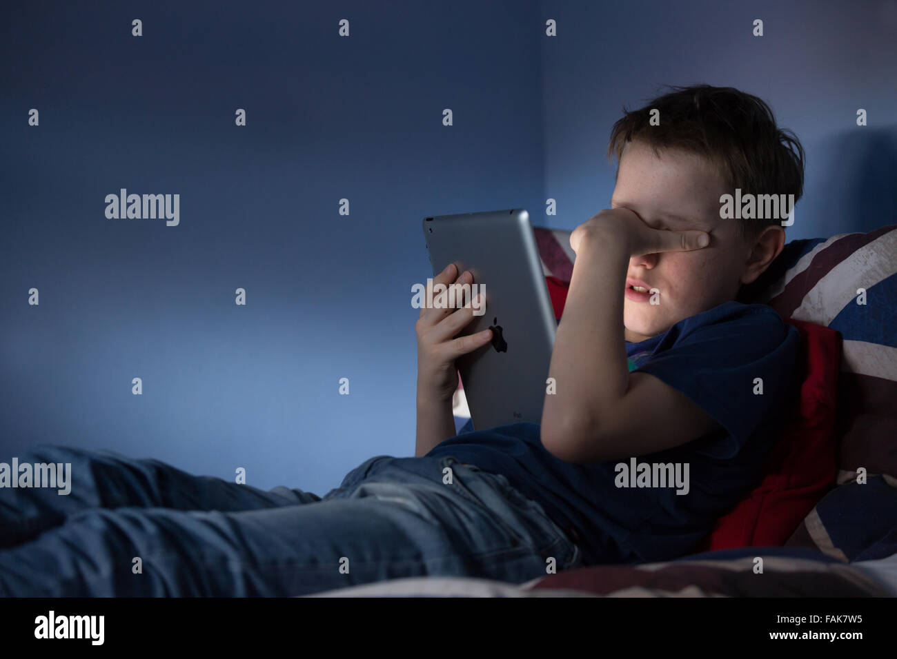 El acoso en línea Cyber Bullying foto de un malestar del muchacho en su habitación mirando mensajes hirientes sobre medios de comunicación social Foto de stock
