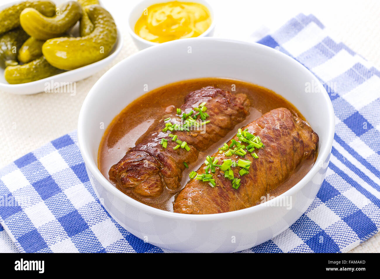 Dos roulades carne en un tazón con la salsa, mostaza y pepinillos Foto de stock