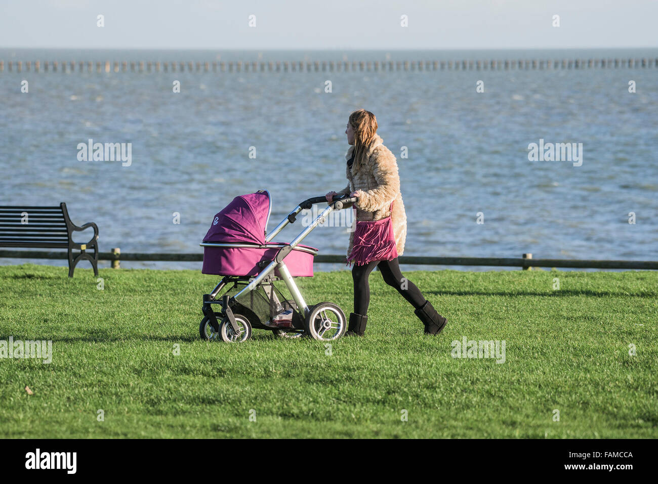 Una madre empuja un cochecito en un parque en East Beach en Shoeburyness, Essex, Reino Unido. Foto de stock